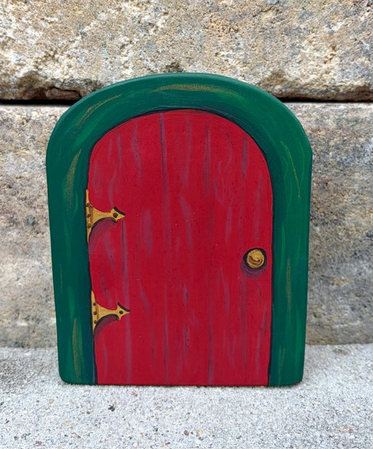 The hand-painted red and green wooden Julenissen door photographed against a stone wall