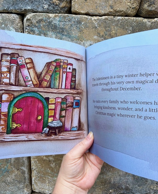 The storybook held open to a watercolor spread of the little red door on a bookshelf