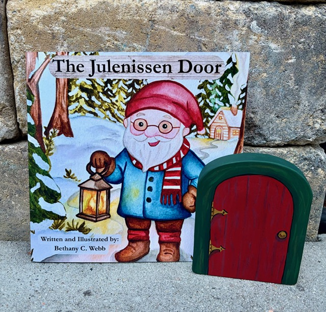 The Julenissen Door storybook standing beside the hand-painted wooden door